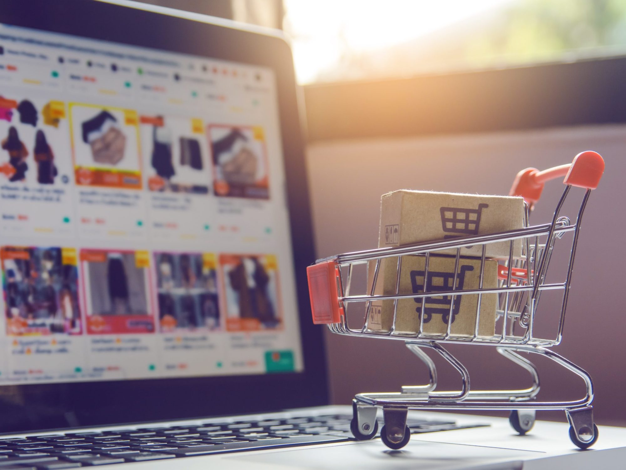Shopping online concept – Parcel or Paper cartons with a shoppin Shopping online concept - Parcel or Paper cartons with a shopping cart logo in a trolley on a laptop keyboard. Shopping service on The online web. offers home delivery